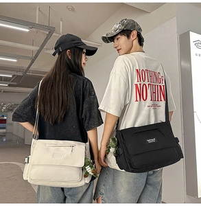 Detail of couple messenger bags in black and beige showing canvas fabric and dinosaur charm
