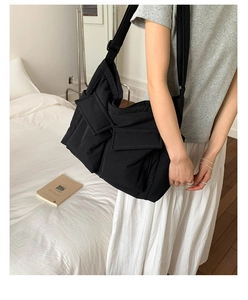 Detail view of black canvas crossbody bag with multi-pocket design and adjustable strap