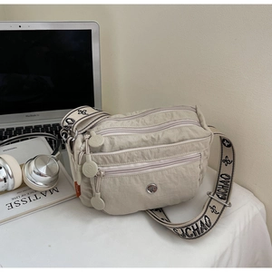 Detail of multi-pocket oxford crossbody bag in beige featuring branded wide strap and zippers