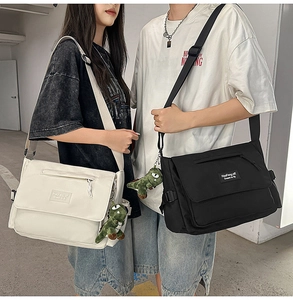 Detailed view of cream and black crossbody messenger bags with green dinosaur pendants