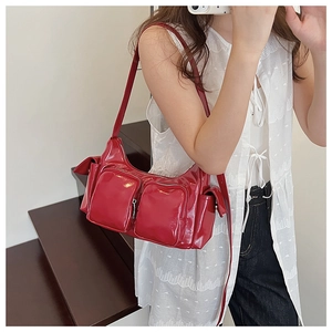 Detail of red glossy shoulder bag with multiple zippered pockets and silver hardware