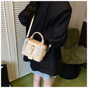 Detail of beige bucket bag with purple checkered scarf handle and gold zipper hardware