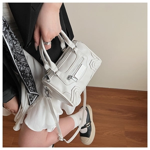 Detalle de bolso bandolera blanco con tachuelas de estilo motero y cremalleras de moda