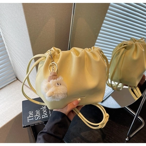 Detailed shot of yellow pleated drawstring bucket bag with a cute plush sheep pendant