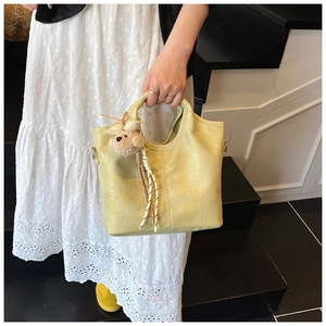 Detail of yellow crocodile embossed handbag with a cute brown plush bear charm