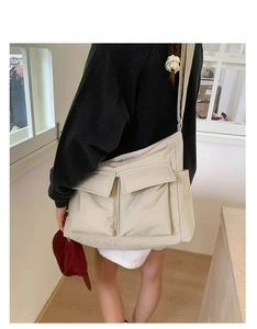 Back view of a model wearing a beige large canvas crossbody bag with multiple pockets