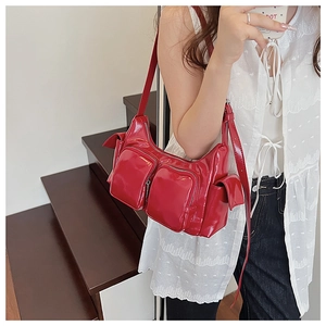Detailed view of red patent leather shoulder bag with multiple utility pockets