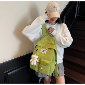 Detail of light green aesthetic backpack with waswac patch and white bear charm