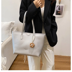 Détail du cabas argenté en cuir à motif litchi avec pendentif perle et fleur