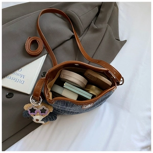 Detail of denim bucket bag interior showing capacity for cosmetics and teddy bear charm