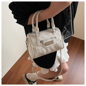 Detalle del bolso Boston crema con textura de piel y logotipo de metal Lazy Breeze