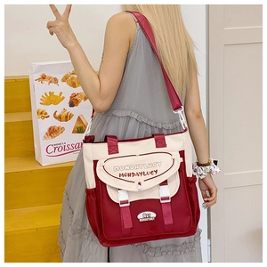 Detail of red and cream canvas messenger bag showing adjustable buckle and side pockets