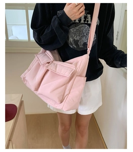Pink canvas messenger tote bag worn by model in a cozy indoor lifestyle setting