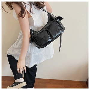 Detail of glossy black patent leather shoulder bag with functional silver zip pockets