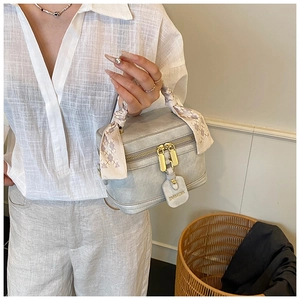 Détail du sac seau en daim gris bleu avec poignée en foulard et étiquette de logo