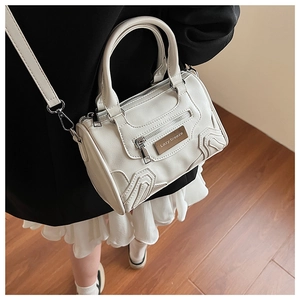 Detalle del bolso Boston blanco crema con cuero PU texturizado y placa metálica de logo