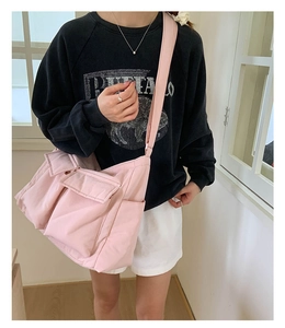 Detail view of pink canvas crossbody bag featuring large front pockets and wide strap