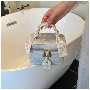 Détail du sac boîte gris avec double zip doré et poignée ornée d'un foulard en soie