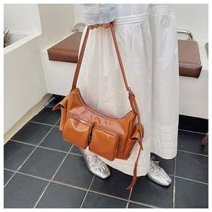 Close-up of caramel brown PU leather underarm bag with functional double zipper pockets