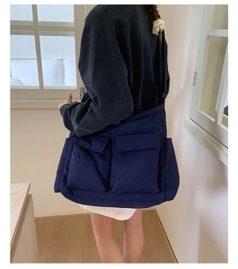 Rear view of a model wearing a navy blue quilted nylon crossbody bag with two front pockets