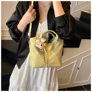Detail of light green bucket bag with crocodile texture and brown plush bear charm