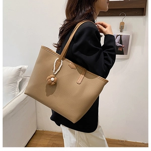 Détail d'un sac cabas en cuir marron avec breloque élégante en perles et fleurs