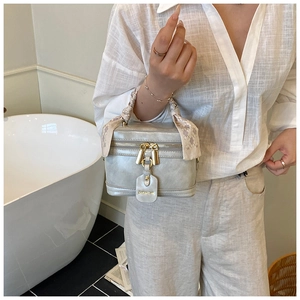 Détail d'un sac seau bleu clair avec poignée en foulard de soie dans une salle de bain