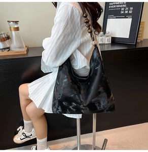 Detail of hobo bag featuring marble pattern texture and wooden bead shoulder strap accent