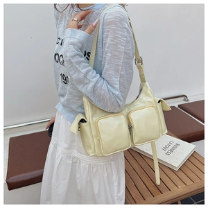 Pale yellow multi-pocket shoulder bag with glossy finish shown in a lifestyle model shot
