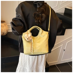 Detail of yellow crocodile pattern bucket bag with a cute plush bear pendant on strap