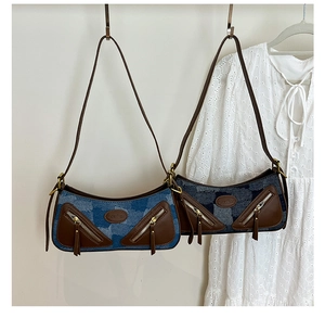 Detail of vintage denim underarm bag with brown leather trim and retro gold hardware