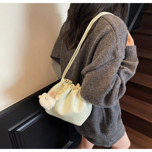 Detail of mint green pleated leather bucket bag with cute white plush sheep pendant