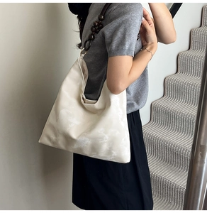 Detail of cream tote bag with unique dark brown beaded strap shown in a lifestyle setting