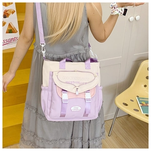 Detail view of purple and beige canvas crossbody bag with buckles and side pockets