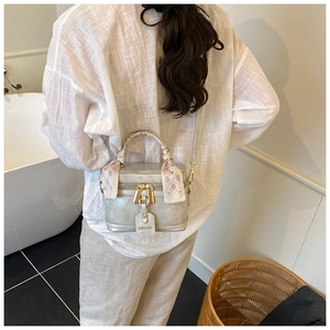 Détail du sac boîte argenté avec poignée en foulard de soie et fermeture éclair dorée