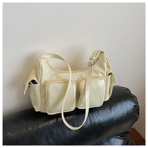Detail of cream glossy patent leather shoulder bag with vintage utility multi-pocket design