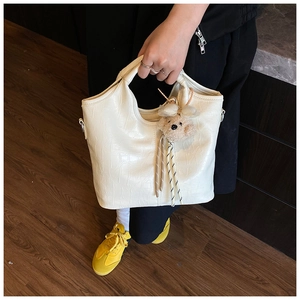 Detail of cream faux crocodile texture handbag with cute plush bear charm accessory