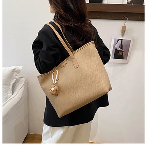 Détail de la texture grainée et du charm floral en perles sur le sac fourre-tout kaki