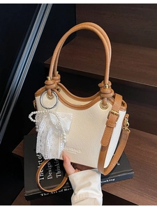 Sac seau bicolore en cuir blanc cassé avec bordure marron et breloque en perles dentelle