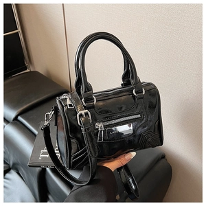 Detalle del bolso Boston negro brillante con asas dobles y placa de logo metálica