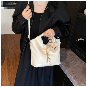 Detail of white crocodile pattern bucket bag with cute brown teddy bear keychain accessory