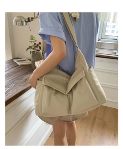 Close-up of beige large capacity canvas messenger bag with double front pockets and strap