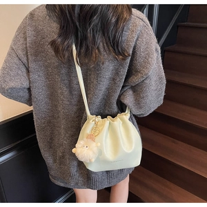 Detail view of mint green pleated bucket bag with cute white plush sheep charm accessory
