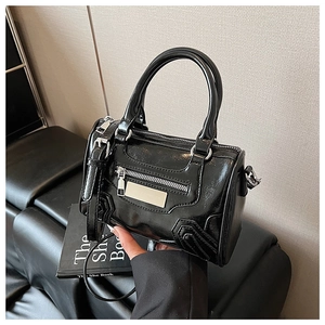 Detalle de mini bolso Boston de charol negro con herrajes plateados y asas superiores