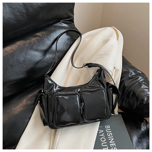 Detail shot of black glossy patent leather shoulder bag with functional zipper pockets