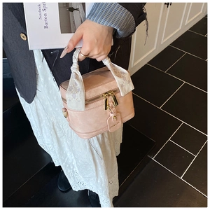 Détail d'un sac à main en cuir rose avec un foulard en soie à carreaux gris sur la poignée