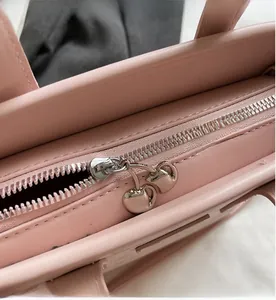 Detail of pink leather bucket bag showing smooth silver zipper with cherry charm