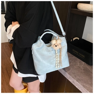 Detail of light blue crocodile embossed hobo bag with teddy bear charm and adjustable strap