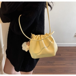 Detail of yellow cloud bucket bag with drawstring closure and cute white sheep charm