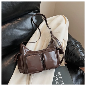 Detail of dark brown glossy shoulder bag with dual zipper pockets and silver metal hardware
